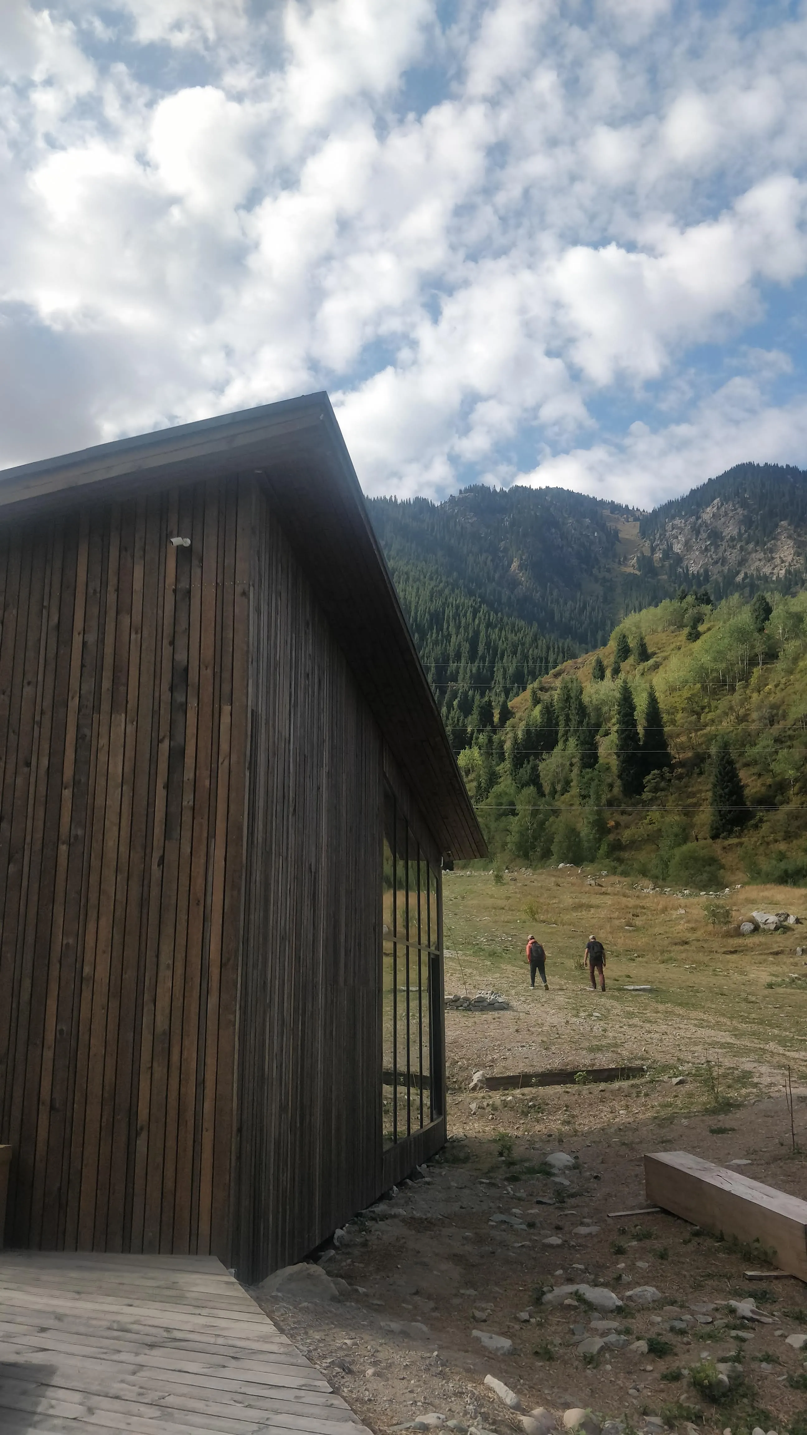 The wooden visitor centre at Ayusai, with two walkers heading off up the track towards the wooded slopes