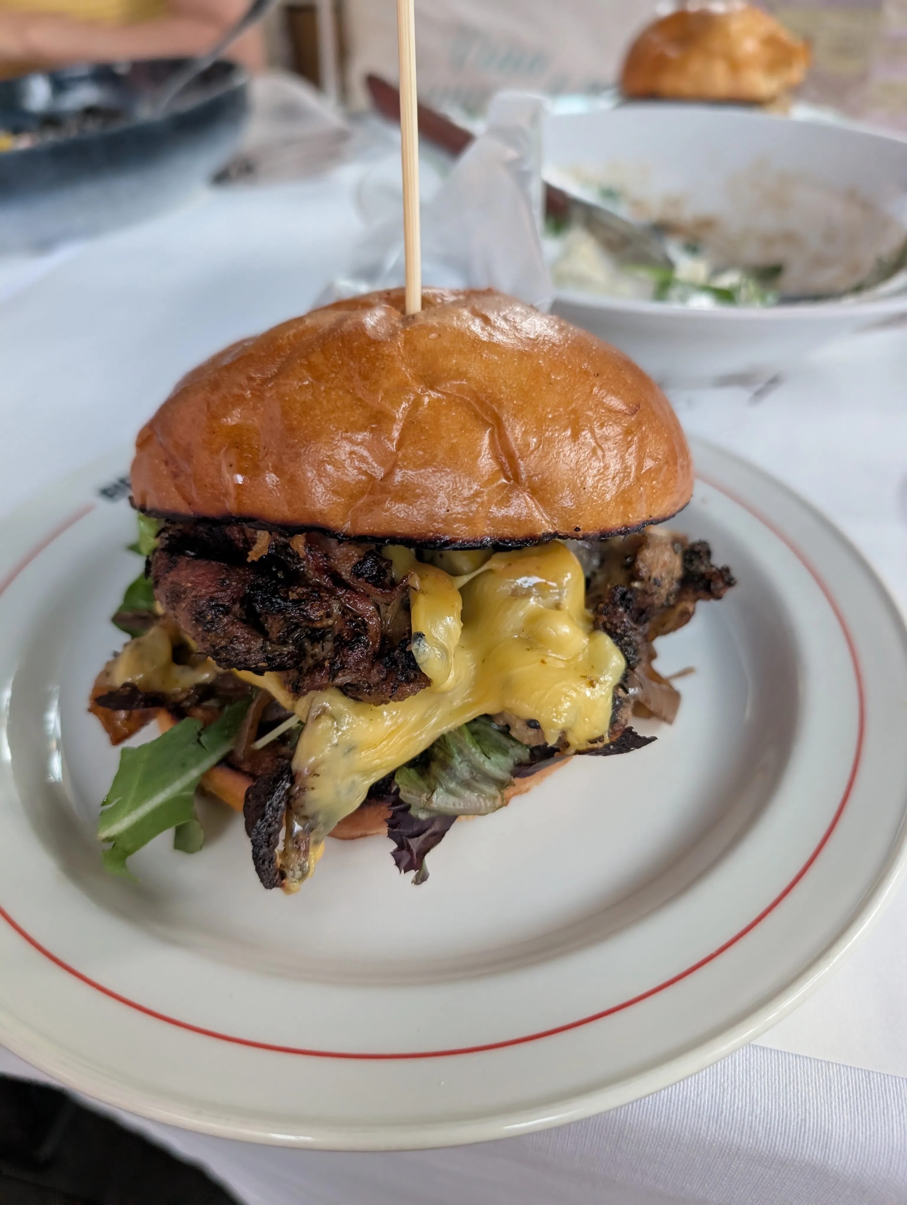 A pulled-beef burger with melted cheese and greens on a brioche bun, on a white plate at Beefeater