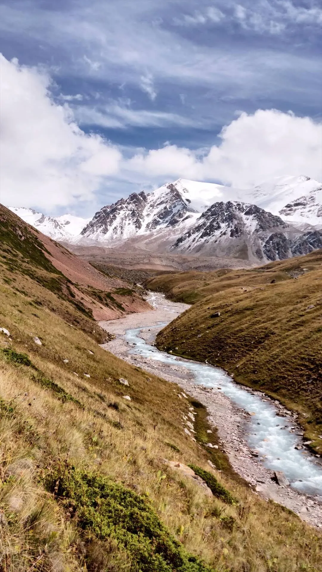 A broad glacial valley in the same range, a braided river running through grass and scree towards a snow-covered peak at its head