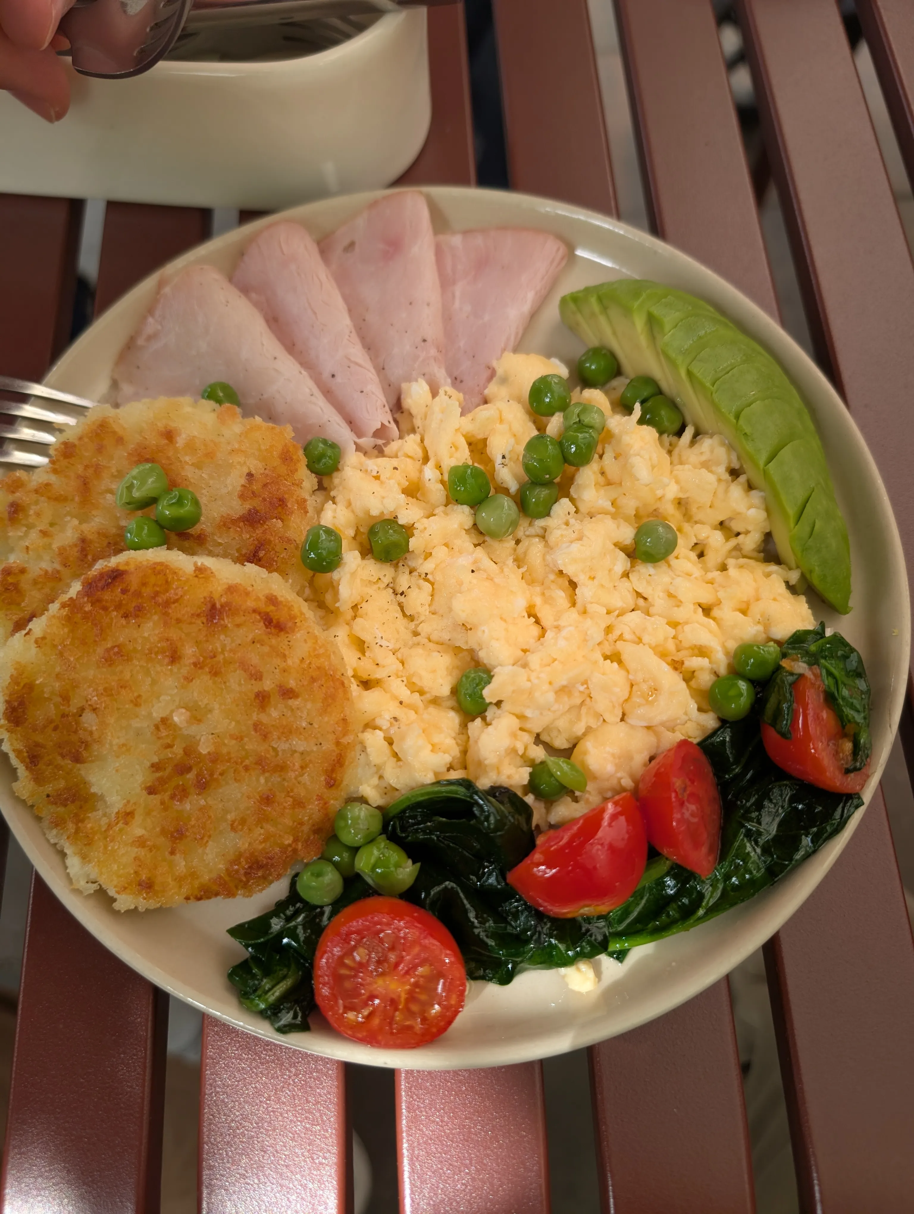 A breakfast plate at Julius: potato rosti, ham, scrambled eggs with peas, avocado and spinach