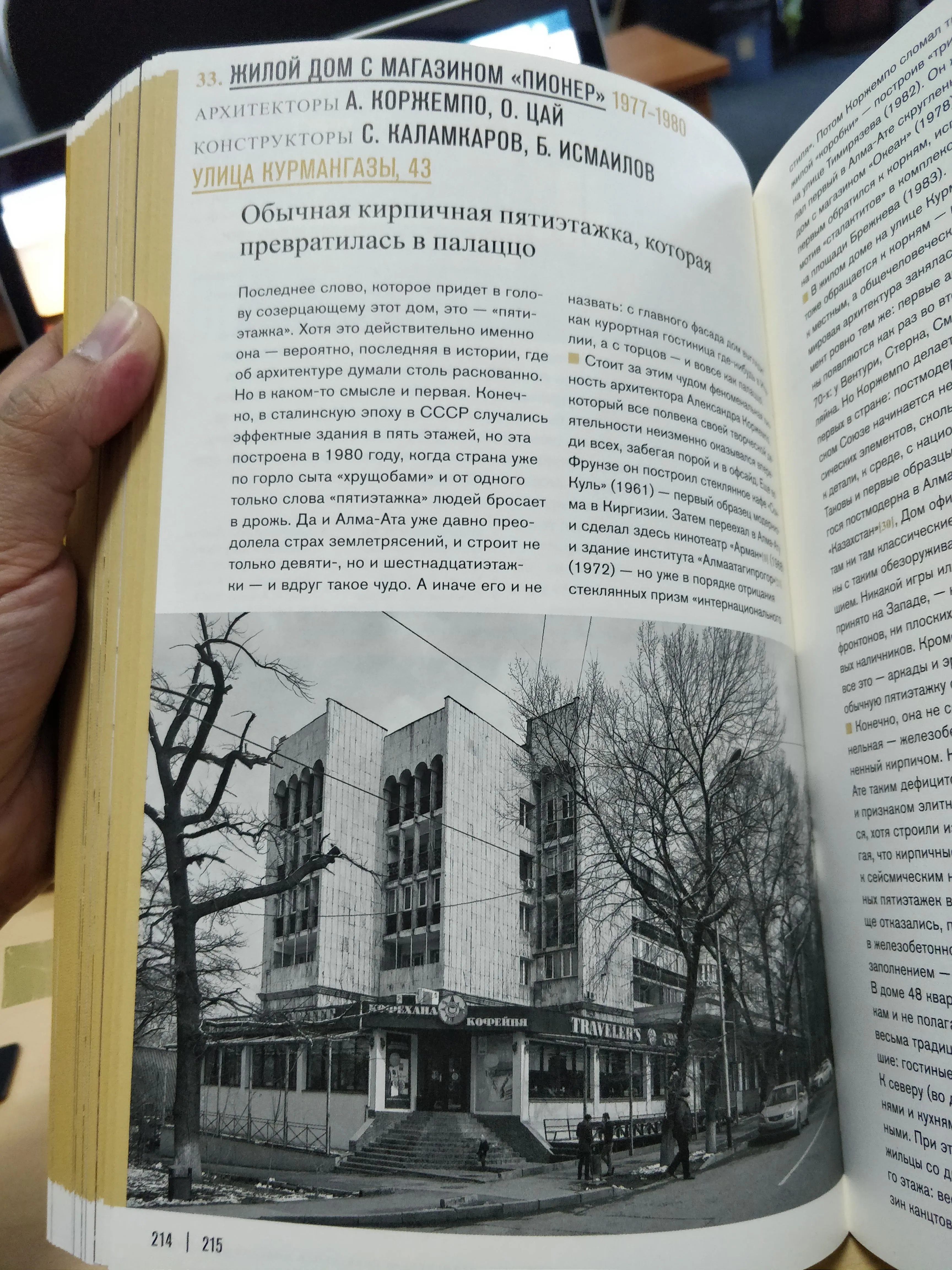A book held open to a black-and-white photograph of a five-storey brick building, the page headed with the address 'улица Курмангазы 43' and a caption in Russian calling it an ordinary brick block that turned into a palazzo