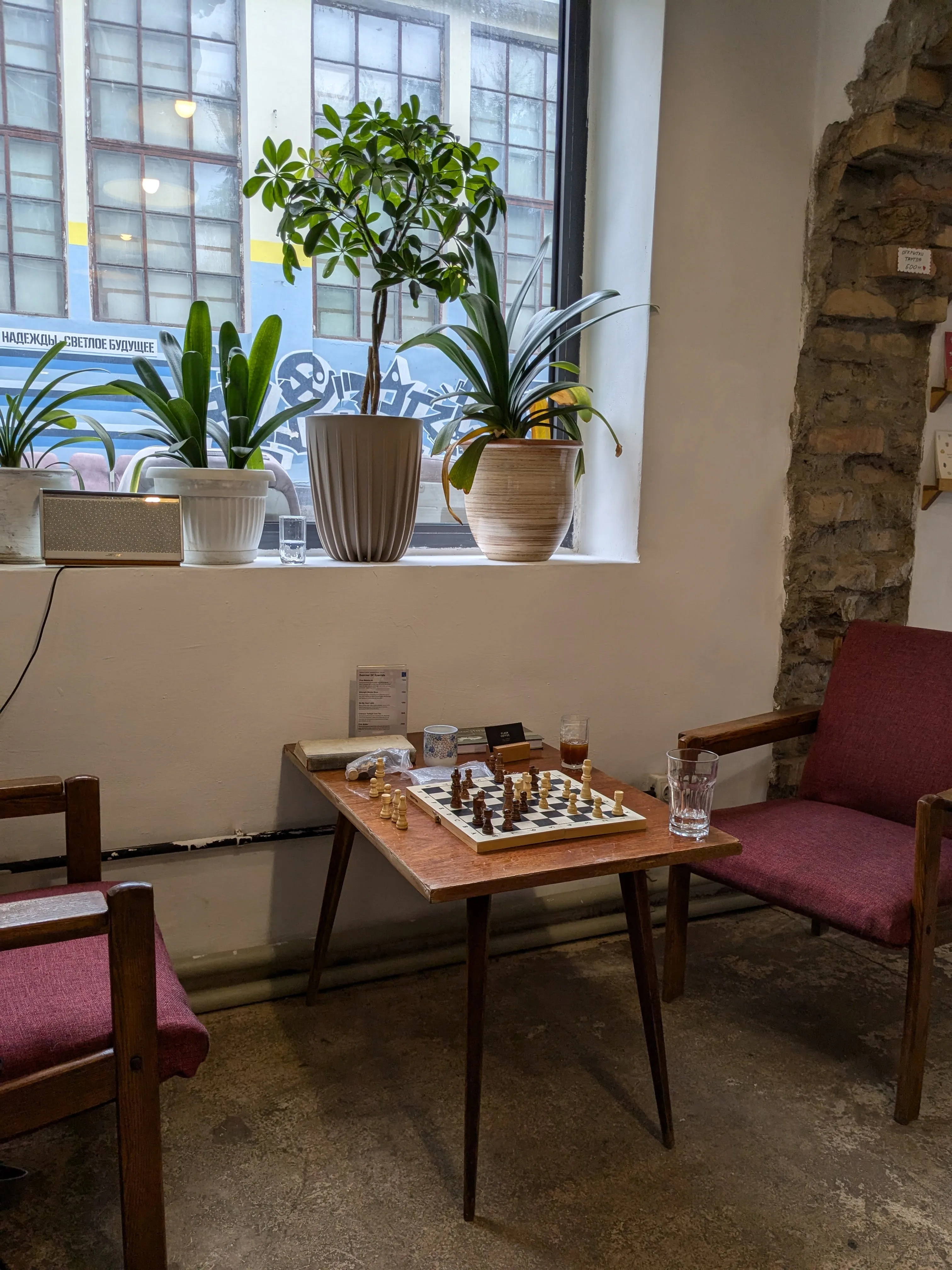 The room at Flask: stone arches, potted plants along the window and a chess set laid out between two low armchairs