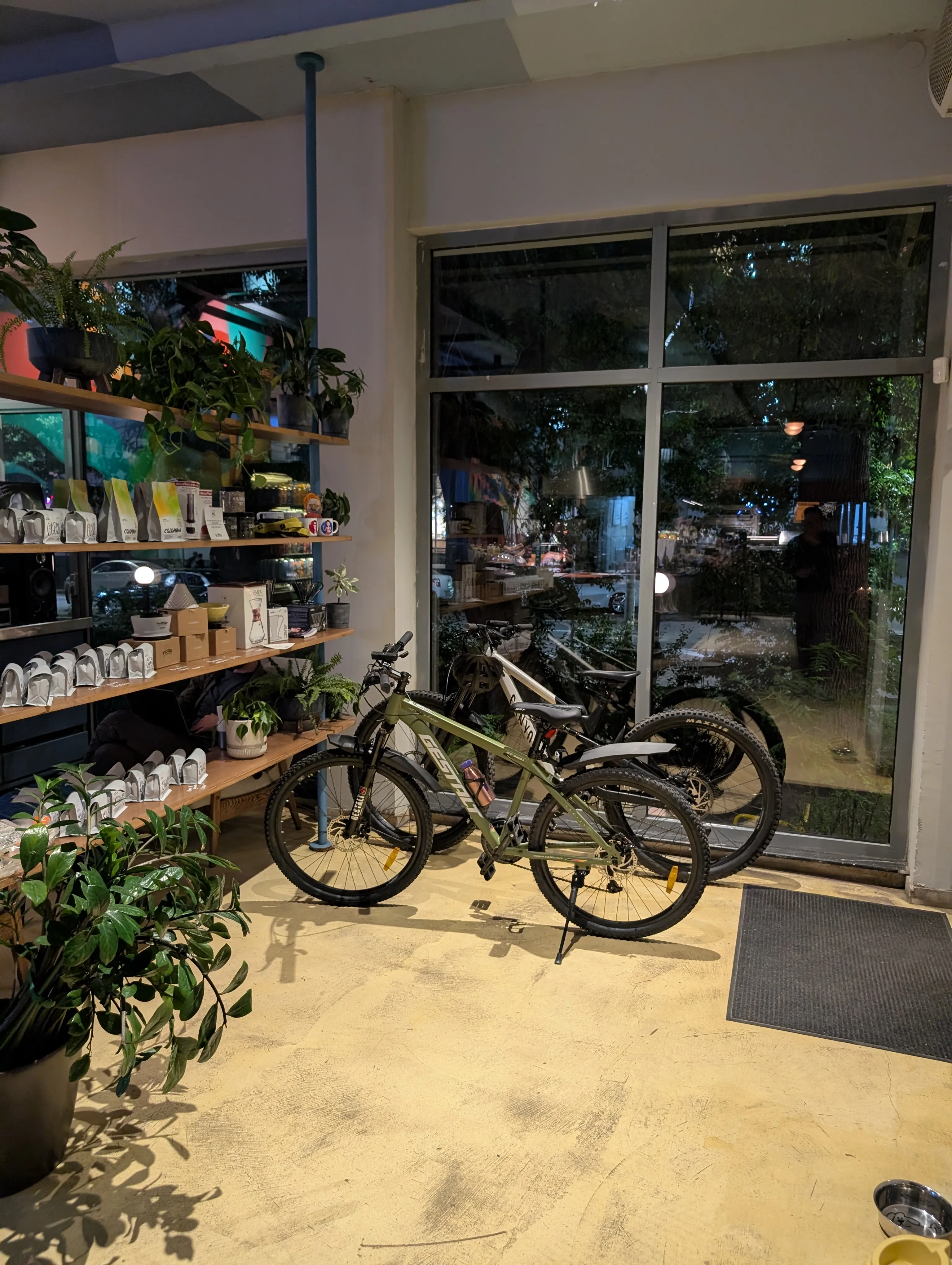 Shelves of retail beans and brewing kit at Coffee Roots, with bikes parked by the window