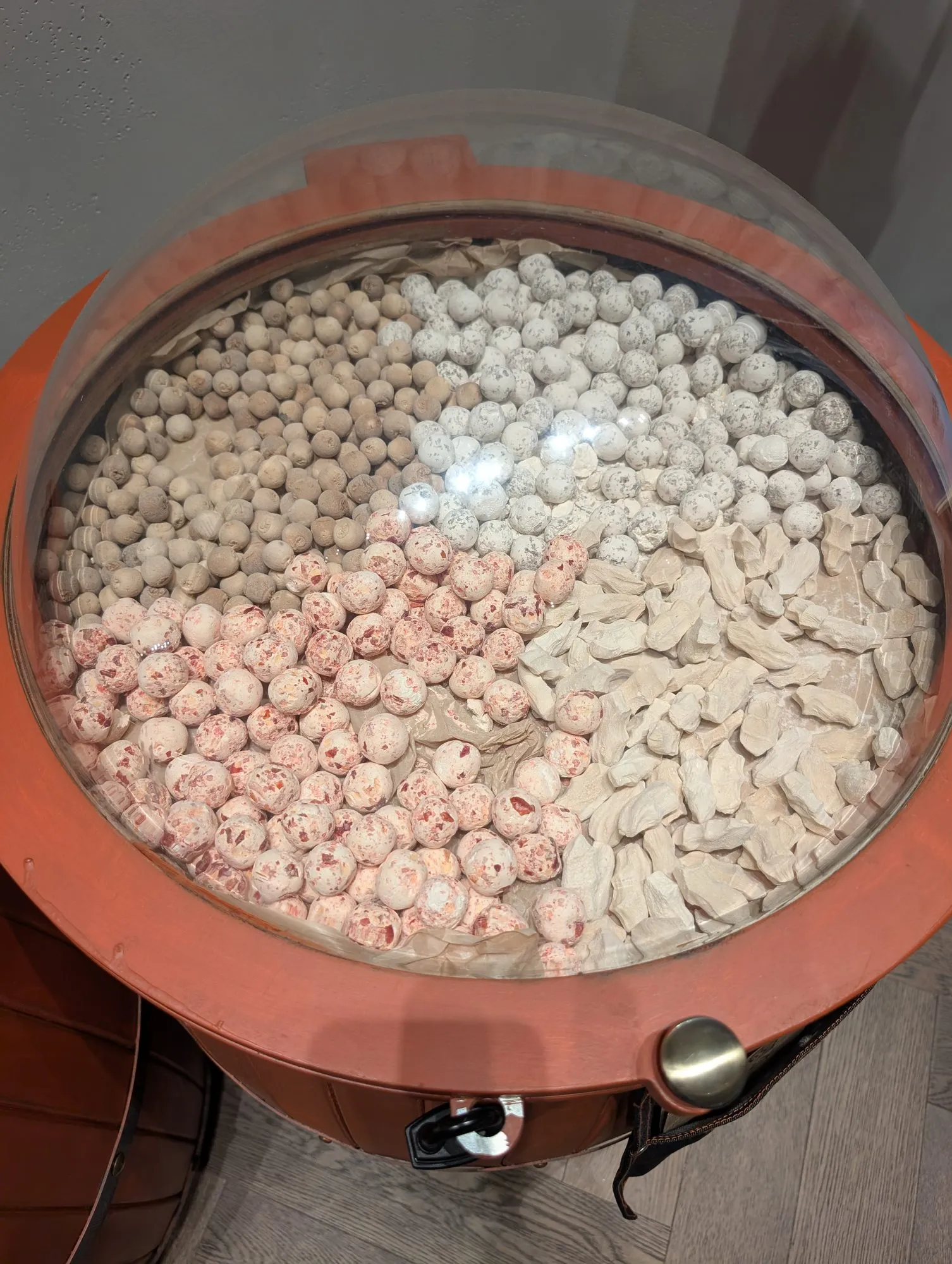 A glass case at Tary holding dried curd balls, most of them white and a batch of them pink