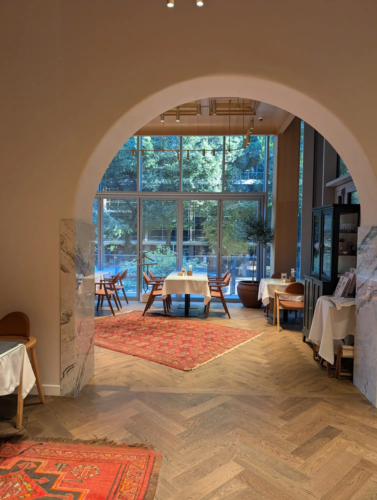 The room at Tary just before seven in the morning: an arched opening onto herringbone parquet, a red rug and laid tables against floor-to-ceiling windows