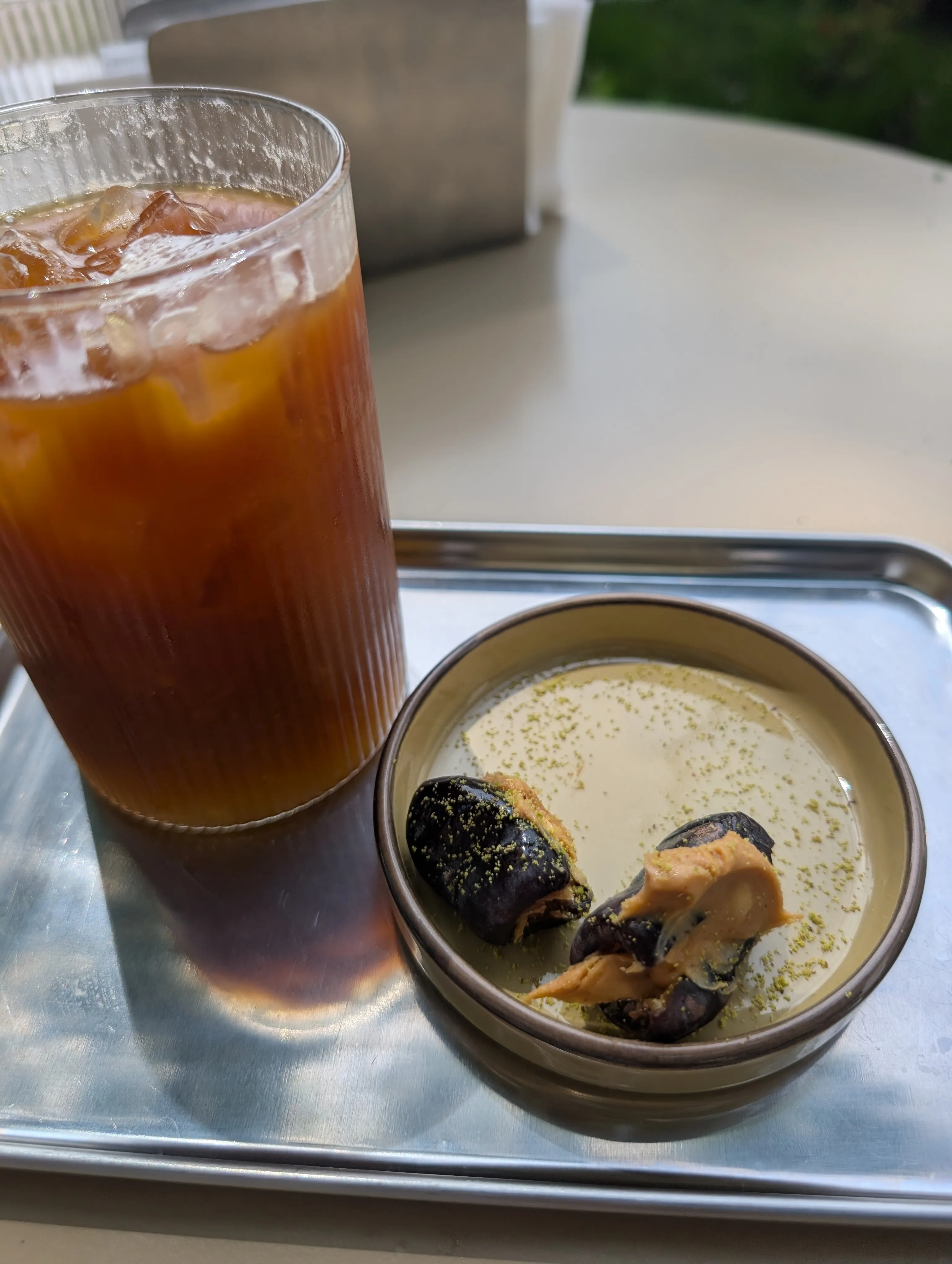 An iced tonic and dates stuffed with nut butter and pistachio at Collab