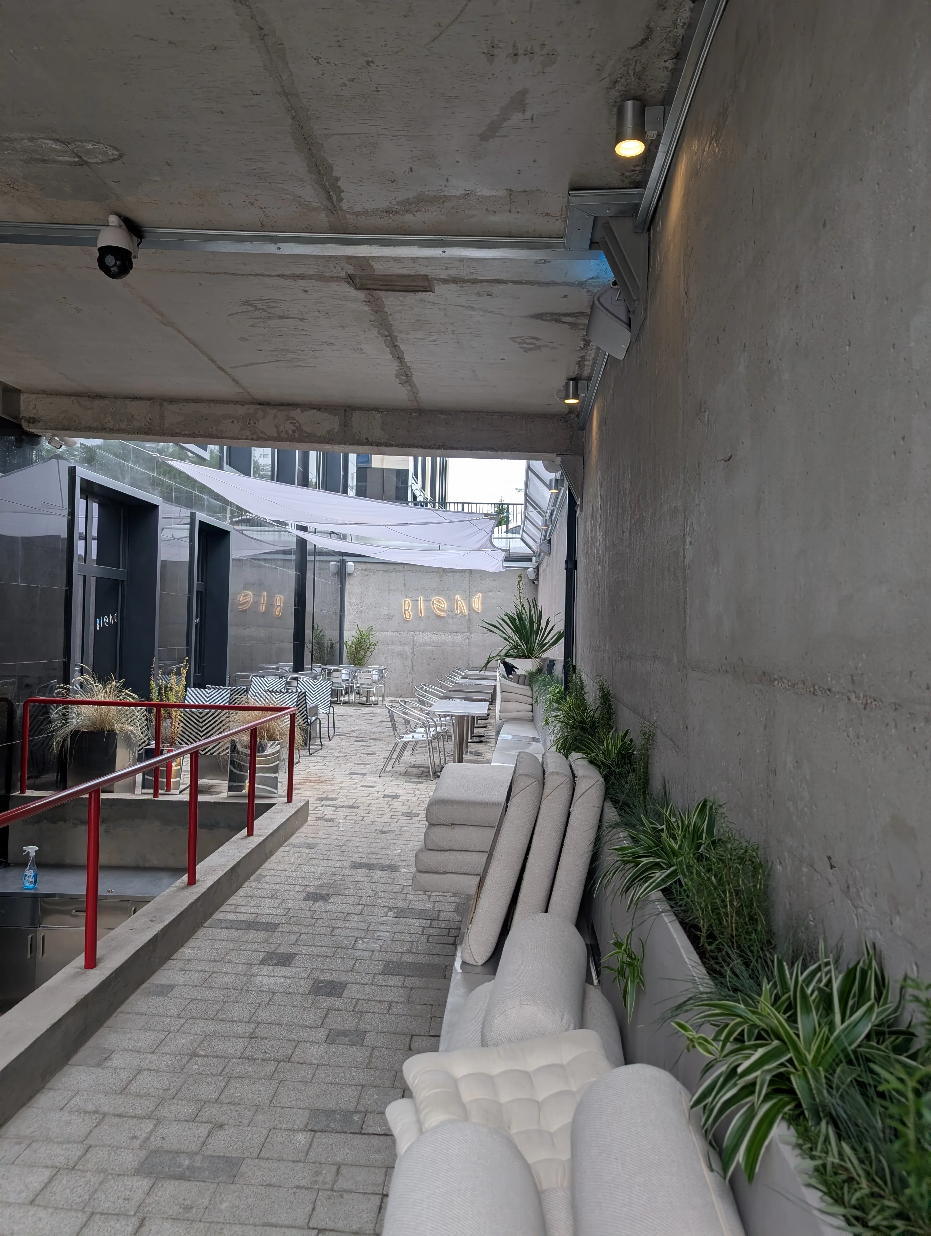 The concrete courtyard at Blend, with the neon sign and shade sails